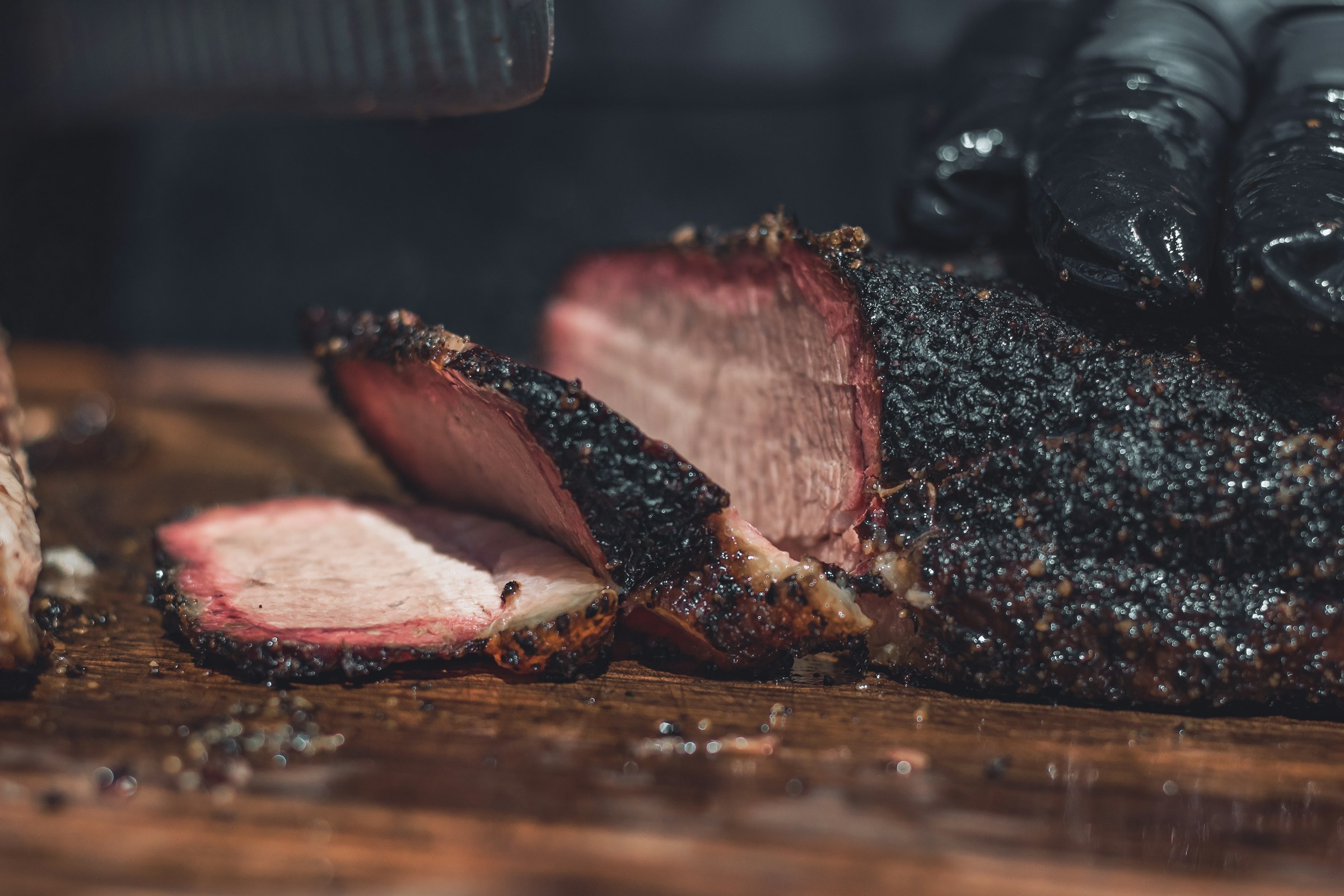 Sliced smoked brisket with a dark bark on a butcher block